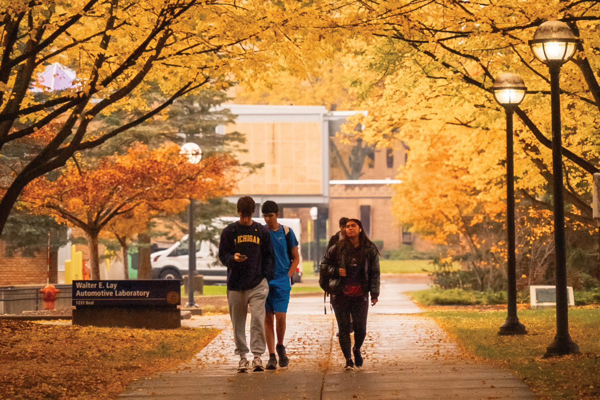Students walking in North Campus with bright yellow and orange autumn leaves