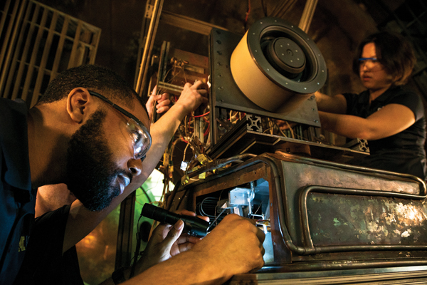 Researchers working on spacecraft equipment in the Plasmadynamics and Electric Propulsion Laboratory