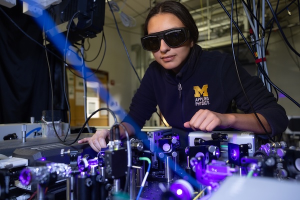 A student wears goggles while working on lasers