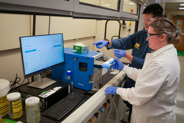 Student and researcher conduct chemical analysis